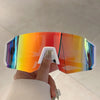 A hand holds a pair of lightweight oversized sunglasses with a gradient lens in various colors.