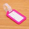 A pink plastic luggage tag with blank lines for name, address, city, and state, attached to a clear strap.