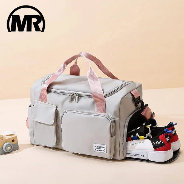 Una bolsa duffel de lona impermeable gris claro con correas y bolsillos rosas, apoyada sobre una superficie beige.