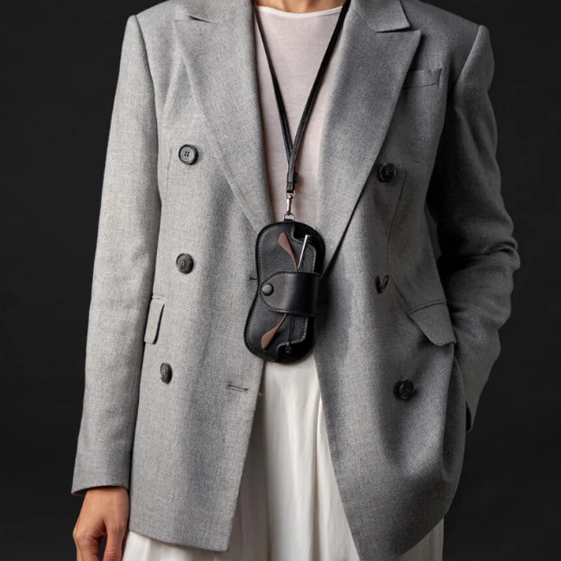 A gray blazer worn over a white top, featuring a black PU leather eyewear storage case hanging from the lapel.