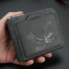 Cartera de cuero gris oscuro con diseño de águila plateada, sostenida en una mano.