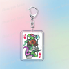 A silver keychain featuring a pixel art design of a Deltarune character with poker cards.