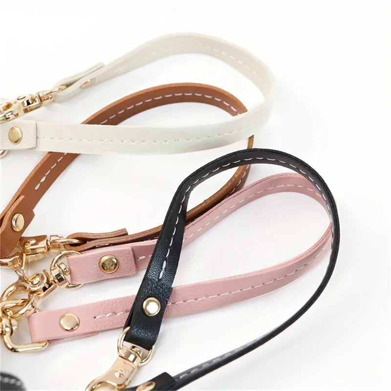 A collection of vintage leather glove holder straps in white, tan, and black.