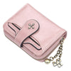 A pink leather mini wallet with a stitched closure and a gold clover charm attached to a chain.