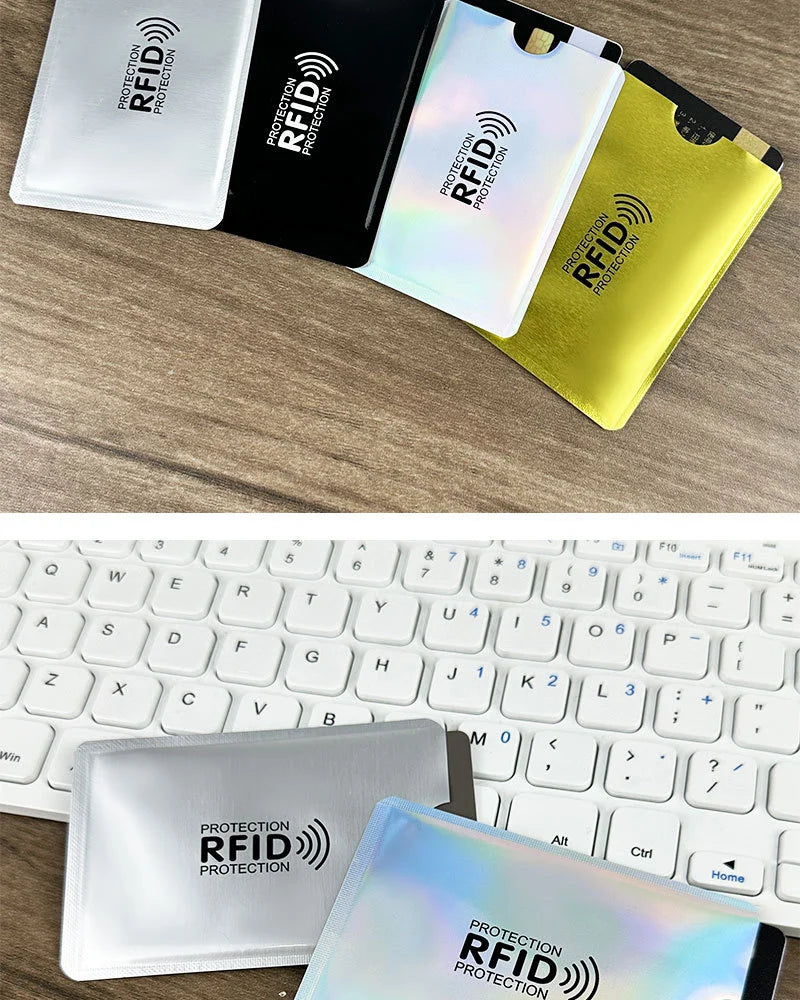 A collection of various colored RFID blocking card sleeves displayed on a wooden surface and a laptop keyboard.
