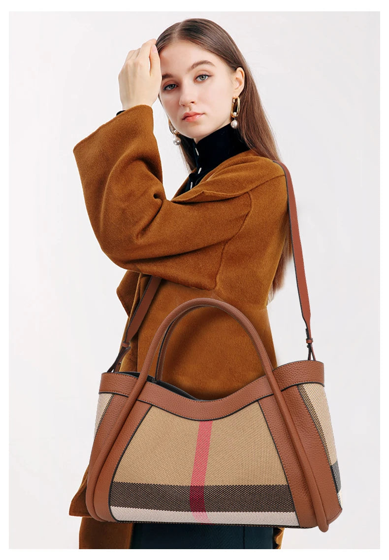 Eine Frau hält eine karamellfarbene karierte Kuhhaut-Tasche mit braunen Lederriemen vor einem hellen Hintergrund.