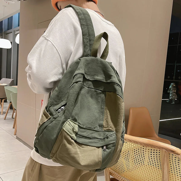 A person is holding a olive green canvas fashion backpack for students and travel in a light indoor setting.