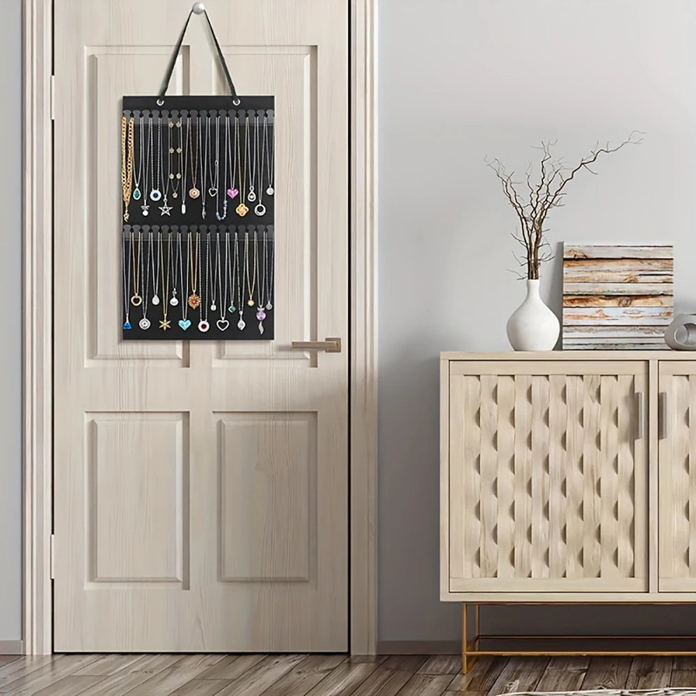 A black wall-mounted organizer displaying various gold and silver jewelry pieces.