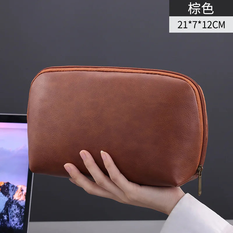 A hand holds a brown leather multi-layer cable organizer pouch with dimensions 21x7x12cm.