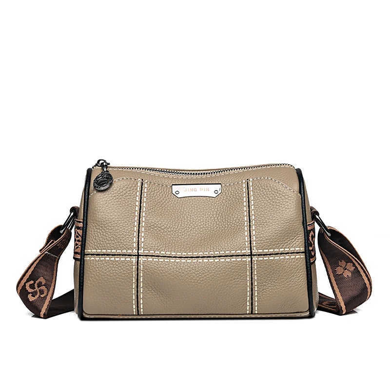 A beige luxury cowhide shoulder bag with stitching and a leather tag is shown from the front.