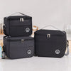 A set of black insulated lunch tote bags with adjustable shoulder straps resting on a white surface.