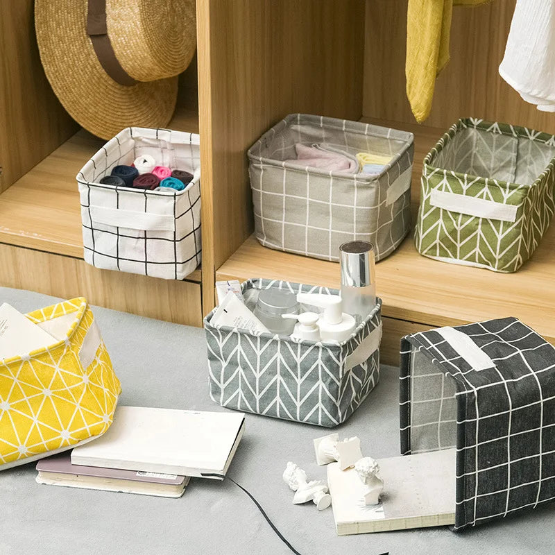 A collection of folded cotton linen storage baskets in various sizes and patterns displayed on a wooden shelf.