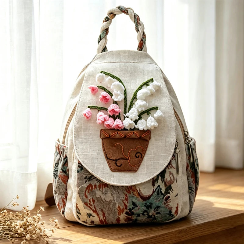 A handcrafted linen backpack in beige and floral patterns with white and pink 3D embroidery.