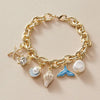 Gold chain bracelet featuring an ocean pearl charm, starfish, and shell accents.