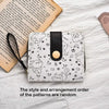 A white coin purse featuring a pattern of cute cat cartoon illustrations and a black leather strap.