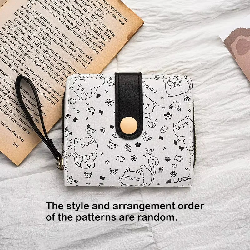 A white coin purse featuring a pattern of cute cat cartoon illustrations and a black leather strap.