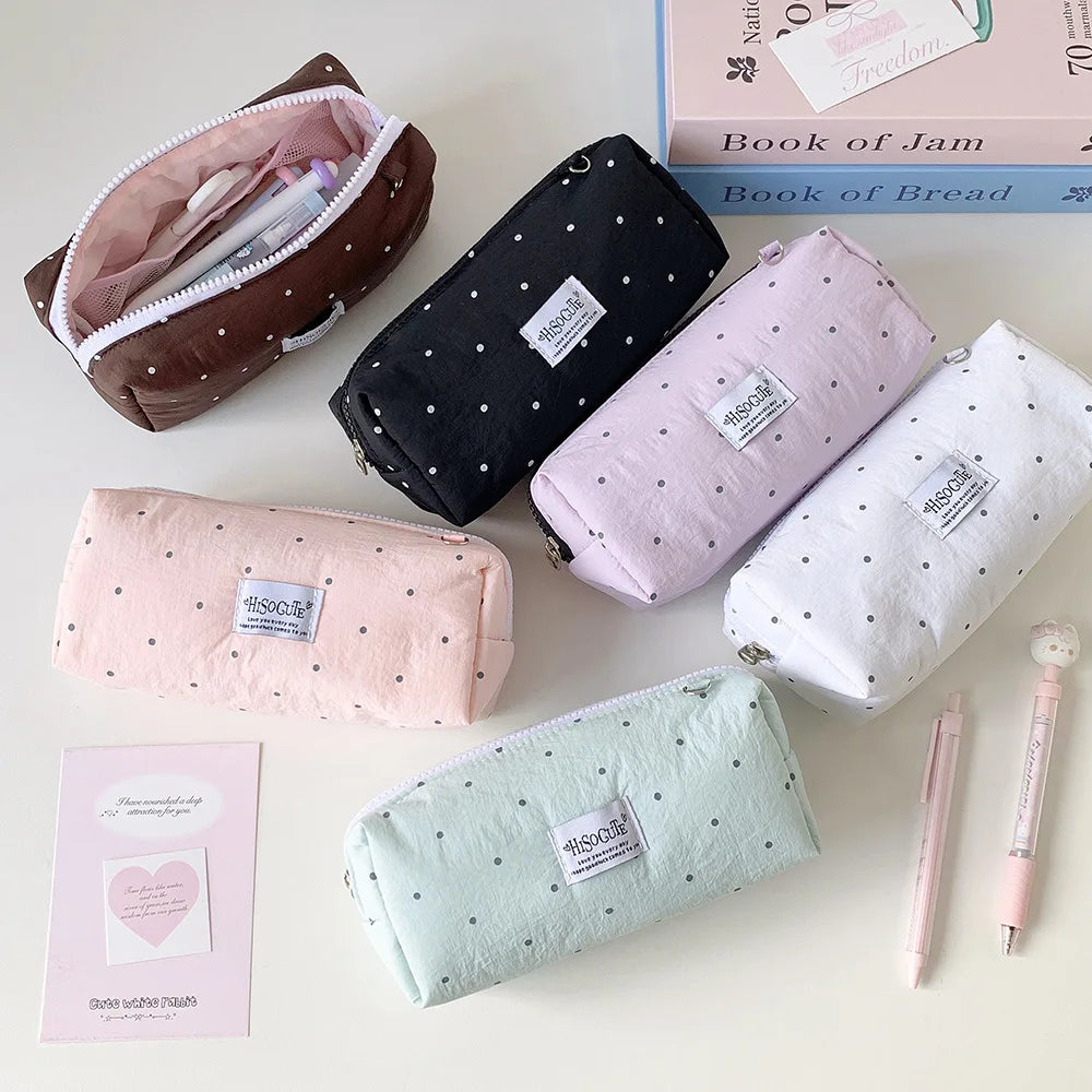 Eine Sammlung von gepunkteten Bleistifthaltern in rosa, weiß und schwarz sowie eine Box mit Marmelade und Brotprodukten.