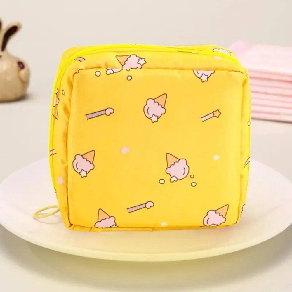A yellow portable pouch with a repeating pattern of pink and white ice cream cones is displayed on a white plate.