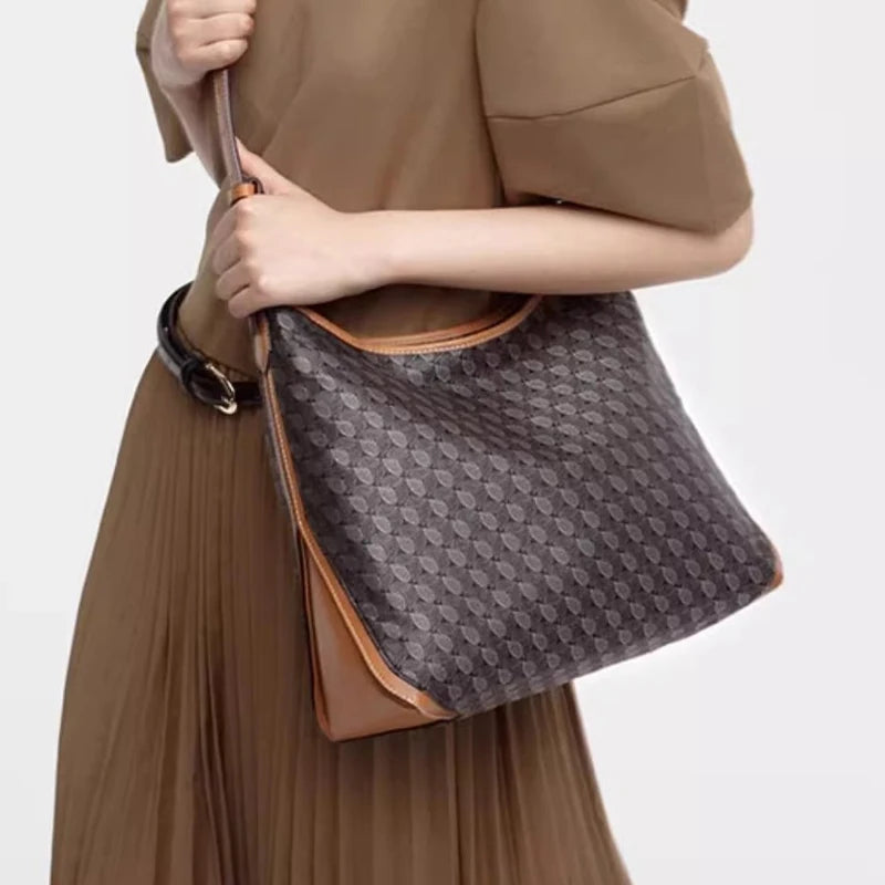 A close-up of a brown geometric embroidery hobo shoulder bag carried by a person wearing a matching brown dress.