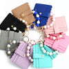A collection of silicone bead and leather card wallets in various pastel colors, including pink, blue, purple, and mint green