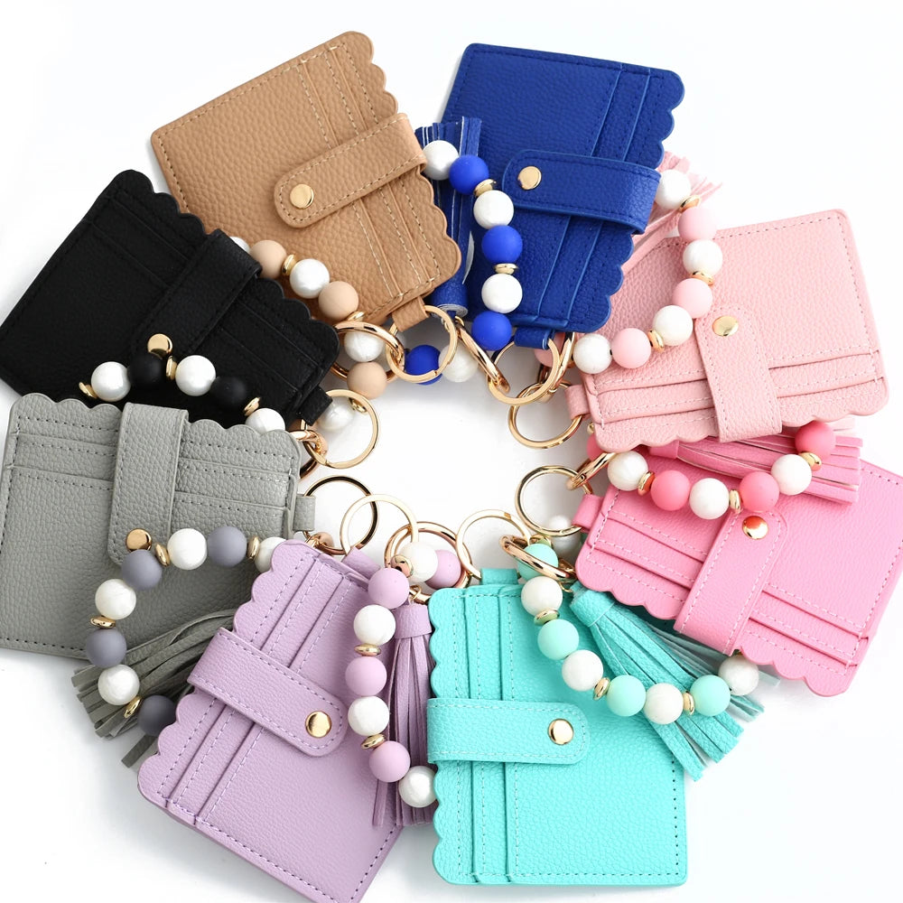 A collection of silicone bead and leather card wallets in various pastel colors, including pink, blue, purple, and mint green