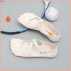 A pair of white women's barefoot five-toe shoes with an adjustable strap and a leather ball are displayed on a light gray sur