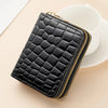 A black PU leather double-zip clutch wallet with a textured pattern resting on a white saucer.