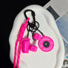 Pink D-shape nylon fitness keychain with a bottle and gym accessories displayed on a white surface.