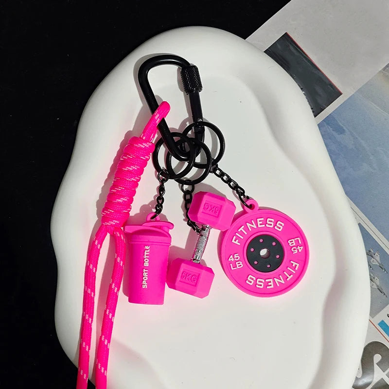 Pink D-shape nylon fitness keychain with a bottle and gym accessories displayed on a white surface.