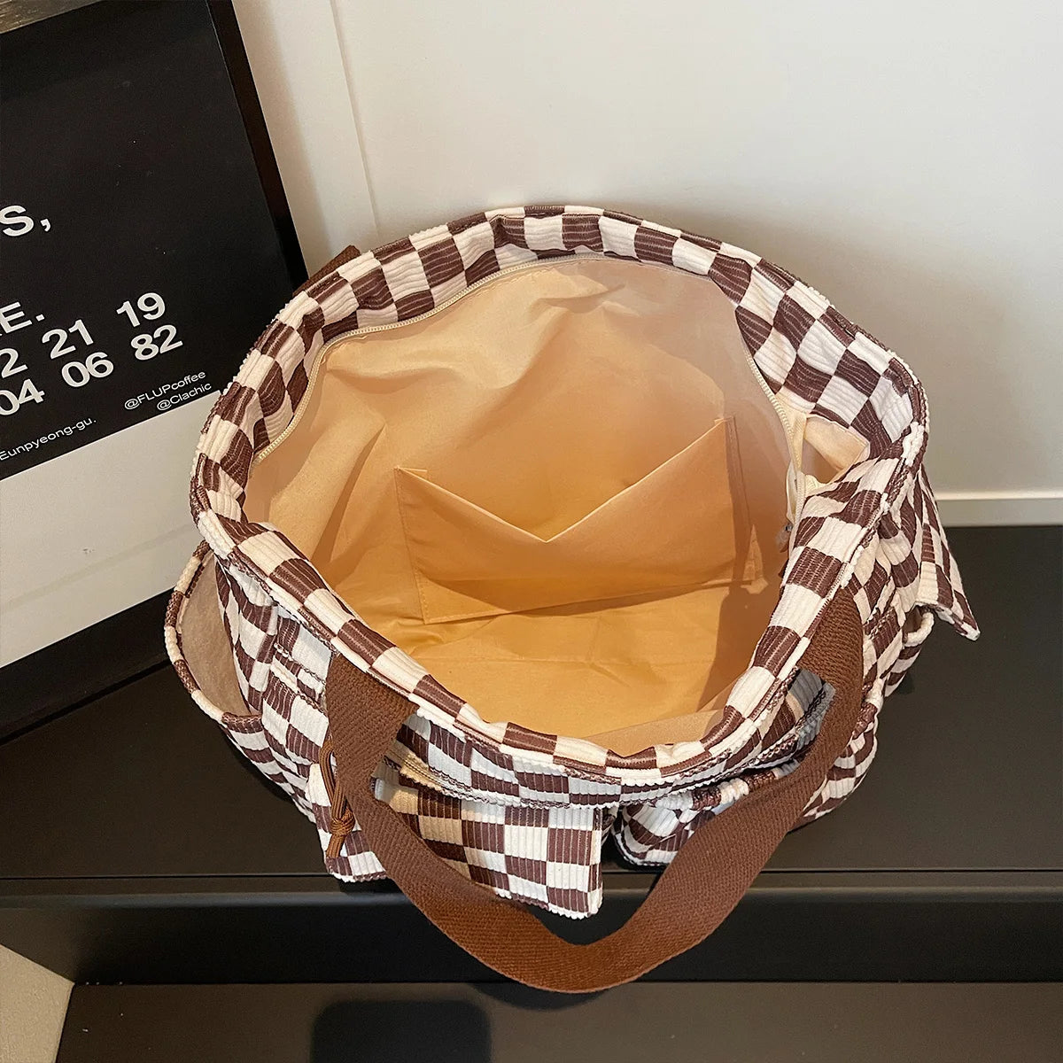 A brown and beige stripe pattern corduroy tote bag is shown from the top, featuring a padded interior.