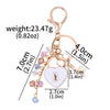 Gold-toned key chain featuring a bow, heart charm, and dangling beads with measurements.