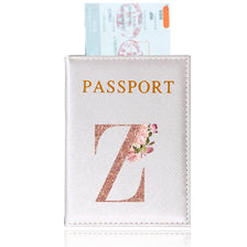Porta-pasaporte de cuero rosa claro con letras doradas y diseño de rosa, junto a una tarjeta de identidad.