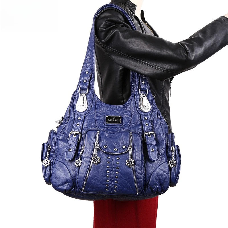 A woman is holding a dark blue vintage PU leather hobo shoulder bag with silver charms and a black leather jacket.