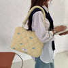 Una mujer sostiene un bolso de computadora acolchado amarillo claro con detalles de lazo azul.