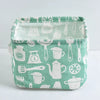 A light green foldable cotton linen storage basket with a transparent lid filled with various kitchen utensils.