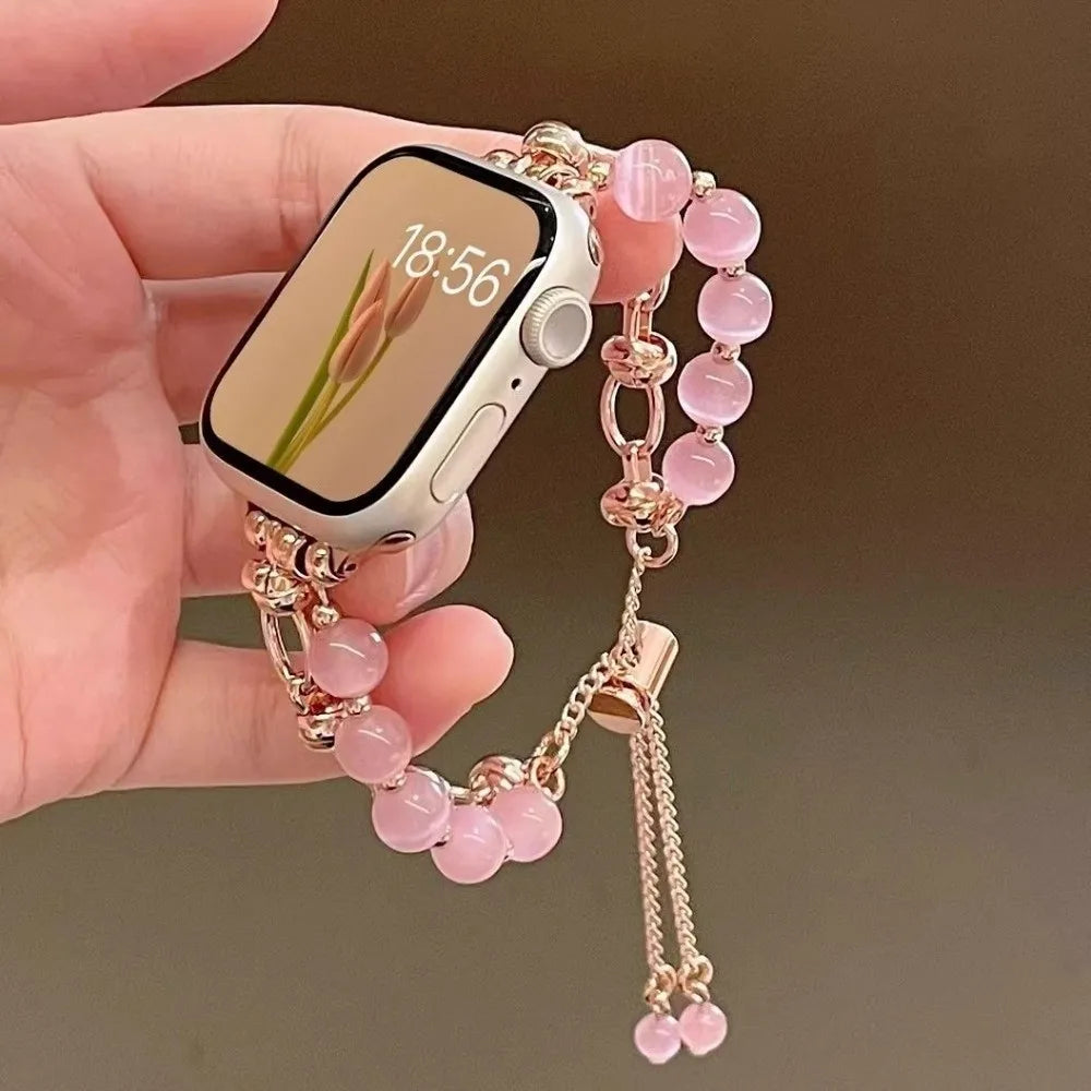 Eine Hand hält ein verstellbares Metallarmband mit rosa Kristallperlen und ein Smartphone, das 18:56 anzeigt.