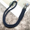 A dark blue hand-woven nylon lanyard with a metal hook is displayed on a textured surface.