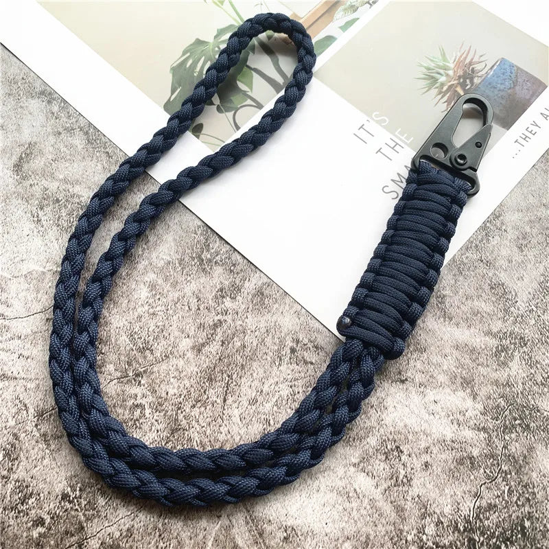 A dark blue hand-woven nylon lanyard with a metal hook is displayed on a textured surface.