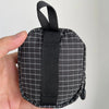 Une pochette utilitaire Dyneema à carreaux noirs pour clés et essentiels tenue dans une main.