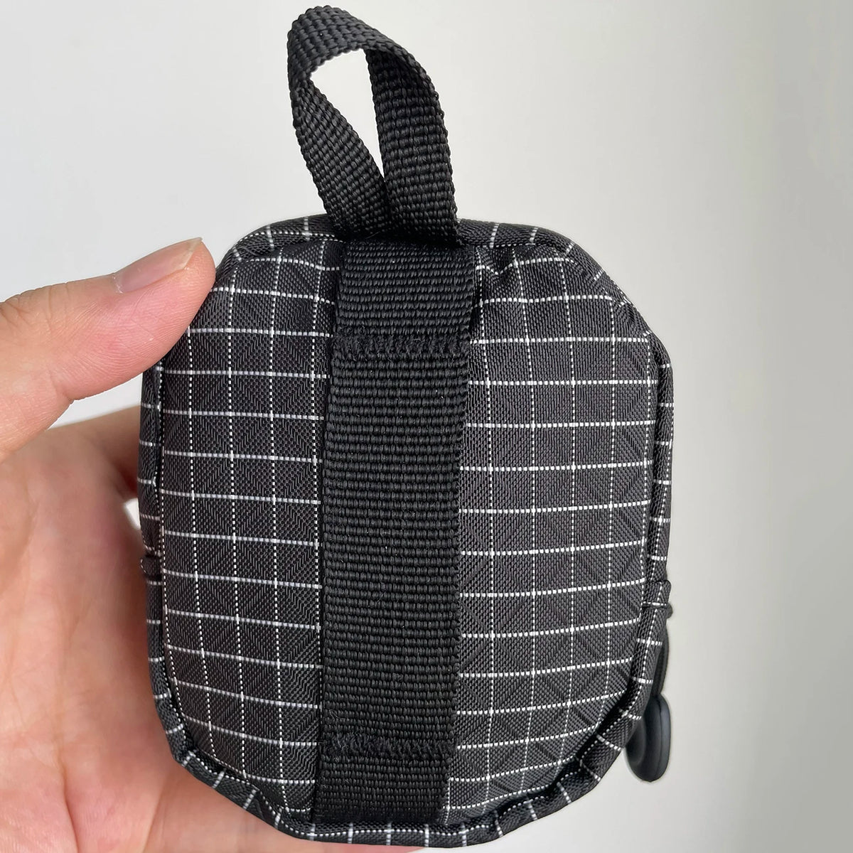 Une pochette utilitaire Dyneema à carreaux noirs pour clés et essentiels tenue dans une main.