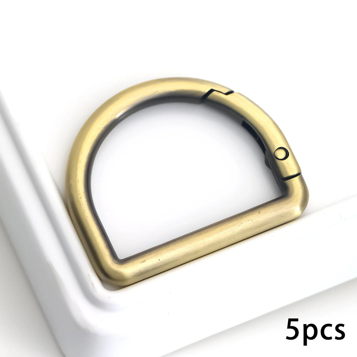 مشابك حلقة نحاسية (D ring) موضوعة على سطح أبيض، مع ظهور خمس قطع.