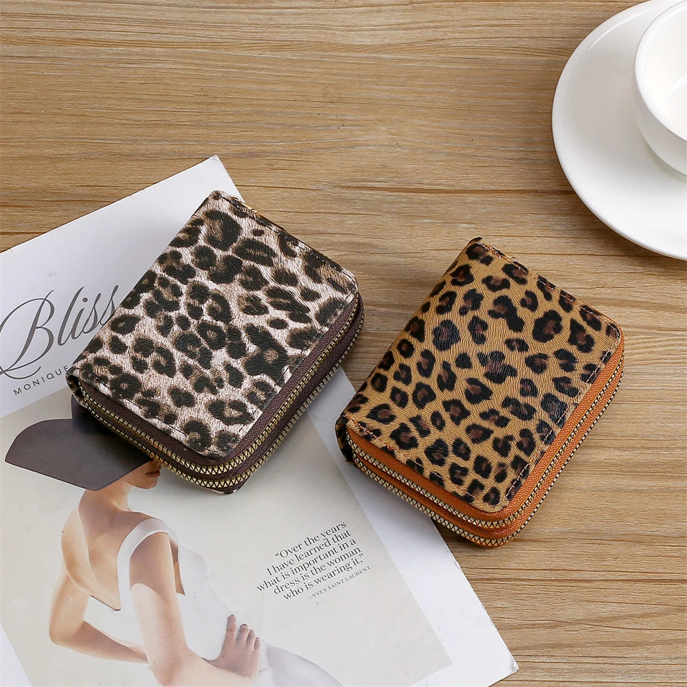 A brown leopard print PU leather compact wallet resting on a wooden table next to a magazine.