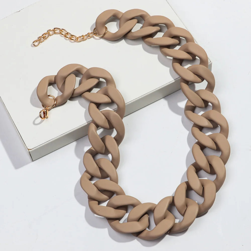 A necklace featuring a matte beige chain and gold accents displayed on a white box.