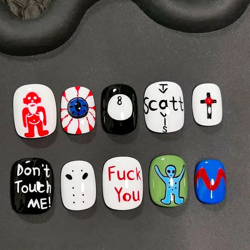 A set of press-on nails featuring various cartoon and text designs on a dark gray surface.
