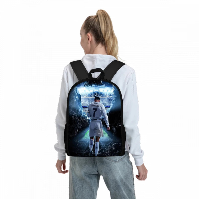 A person is wearing a black backpack featuring a football player theme with a blue and white background.