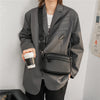 A man wearing a gray blazer and black pants carrying a black PU leather crossbody messenger bag.