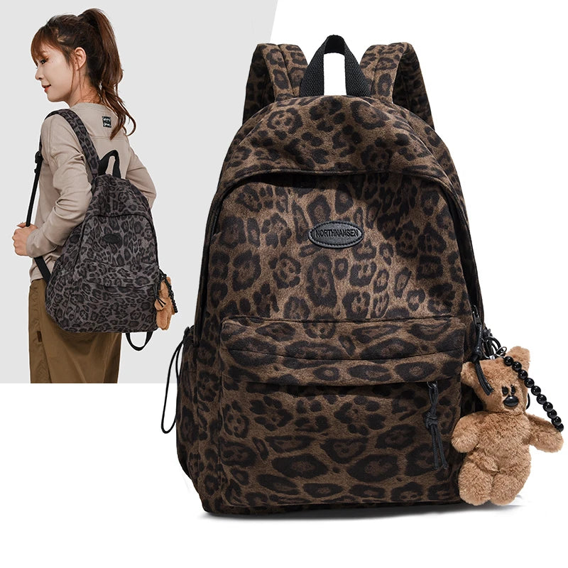 A brown leopard print backpack shown with a model wearing it and a small teddy bear.