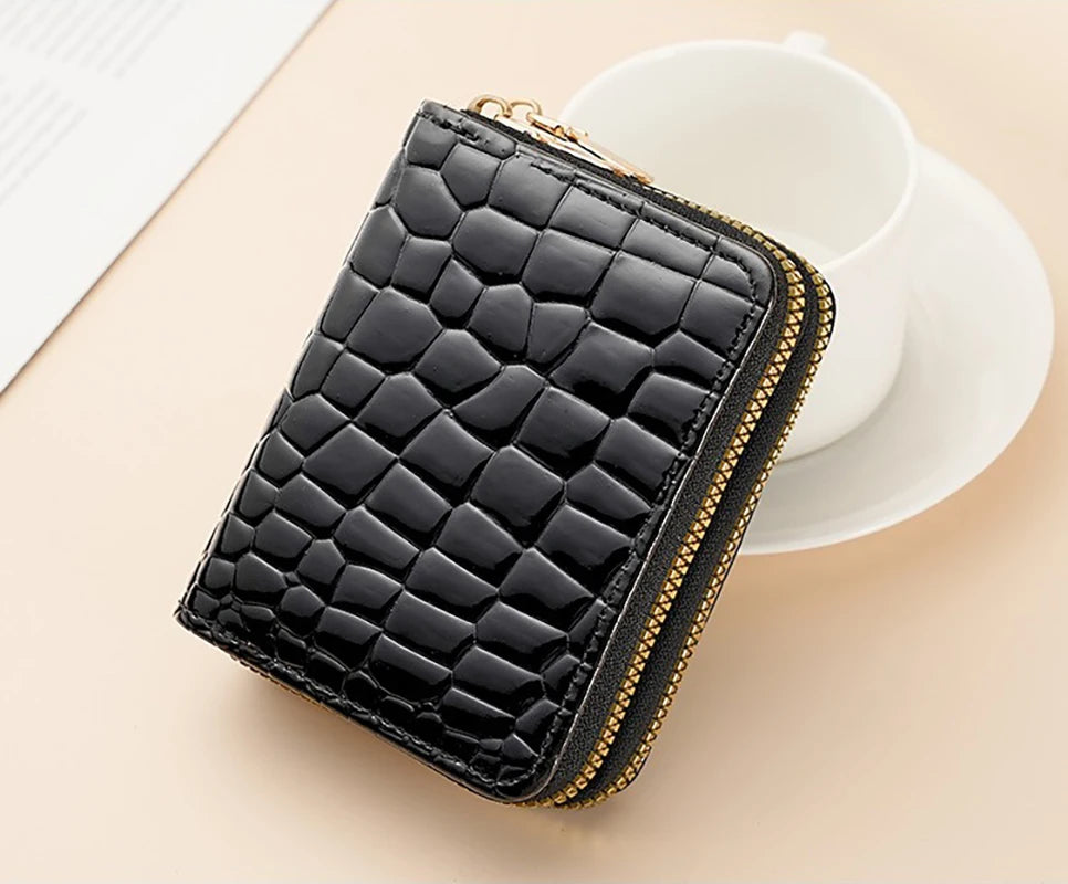 A black quilted PU leather double zipper wallet resting on a light pink saucer next to a white cup.