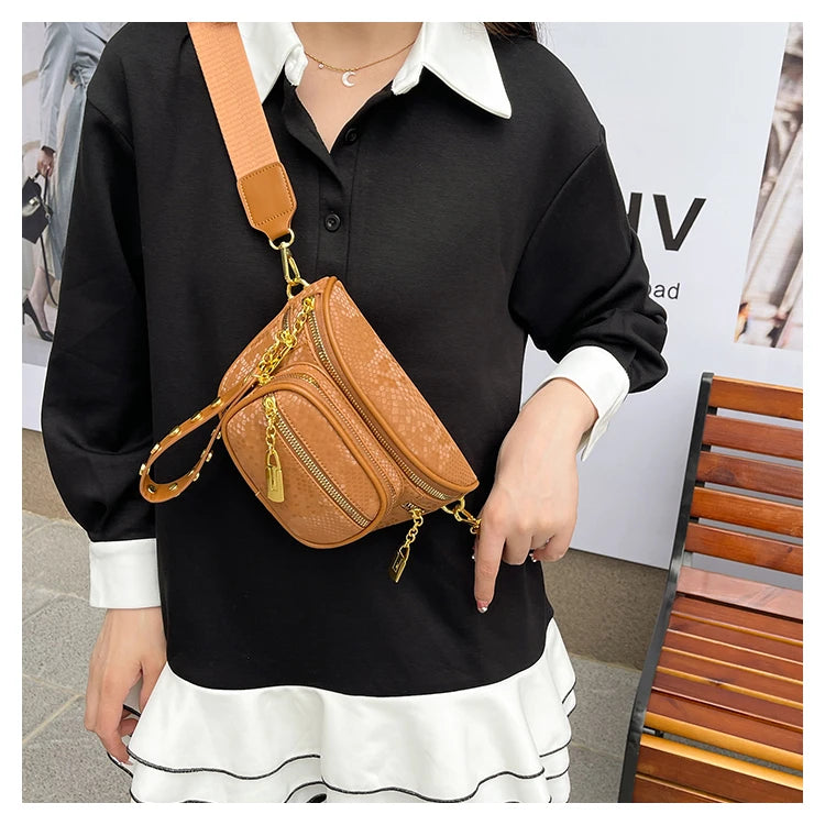 A woman wearing a black shirt and white skirt holds an orange leather Rivet waist bag.