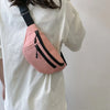A pink nylon waist bag with black straps is worn on a white t-shirt.